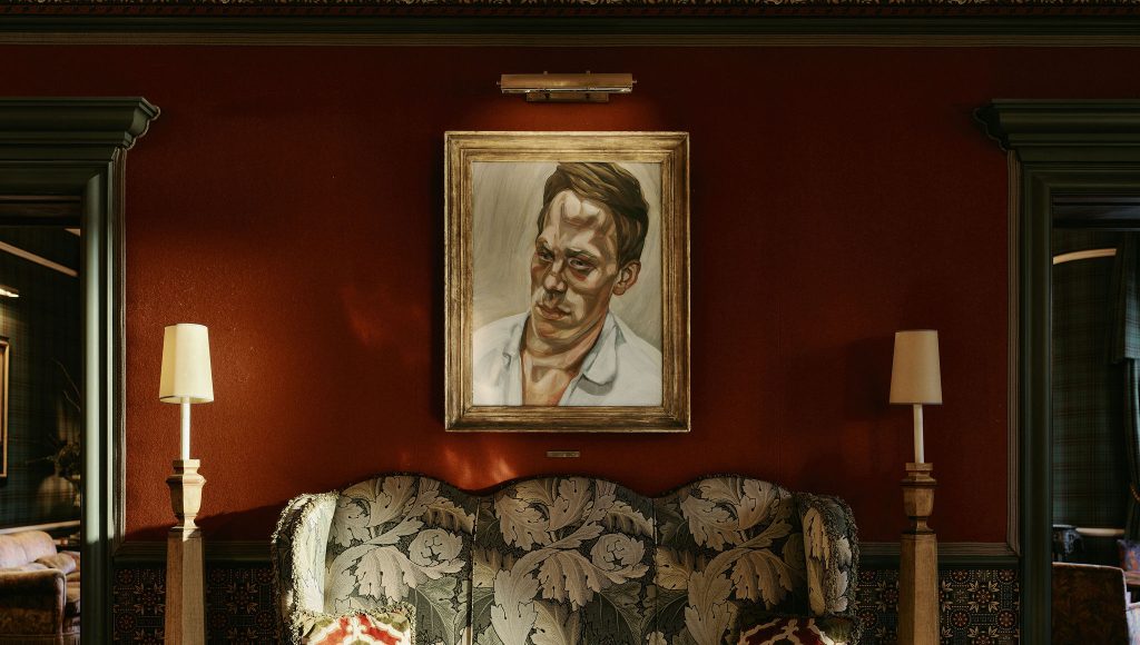 A painting by Lucien Freud hung on an orange wall in the hotel reception
