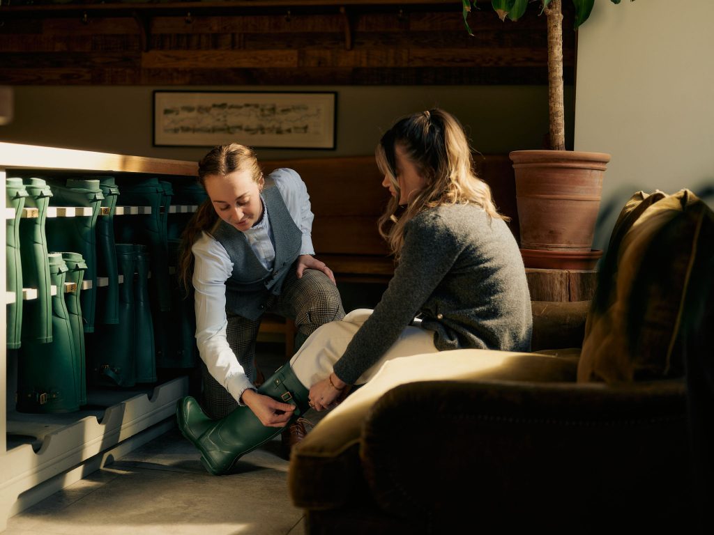 A ghillie team member helping a guest with her Wellington boots