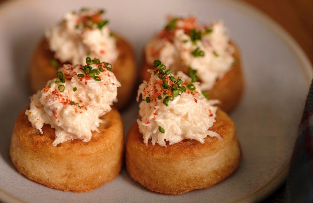 A close up of four crab crumpets on a plate.