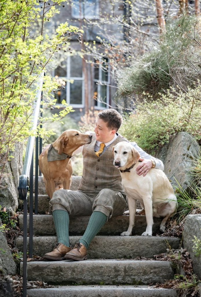 A ghillie sat with two dogs