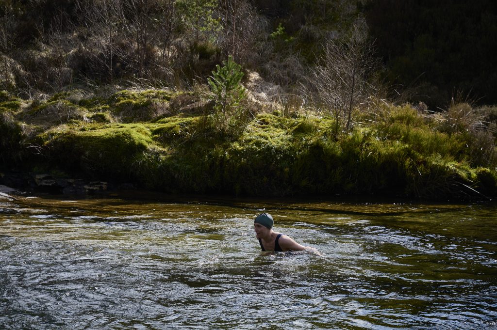 Annie, our wild swimming guide in the water with a swim cap on