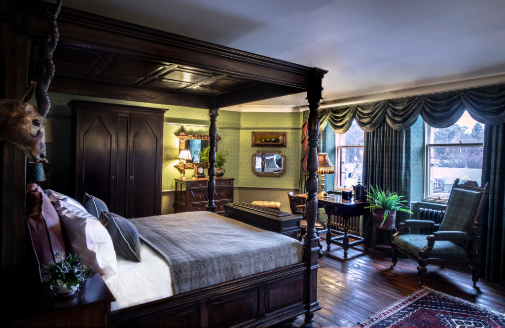 The Highlander suite bed with desk beside windows