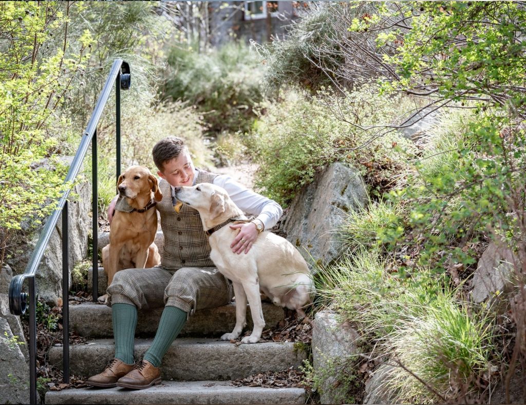 Two dogs with a hotel porter in the Fife Arms garden