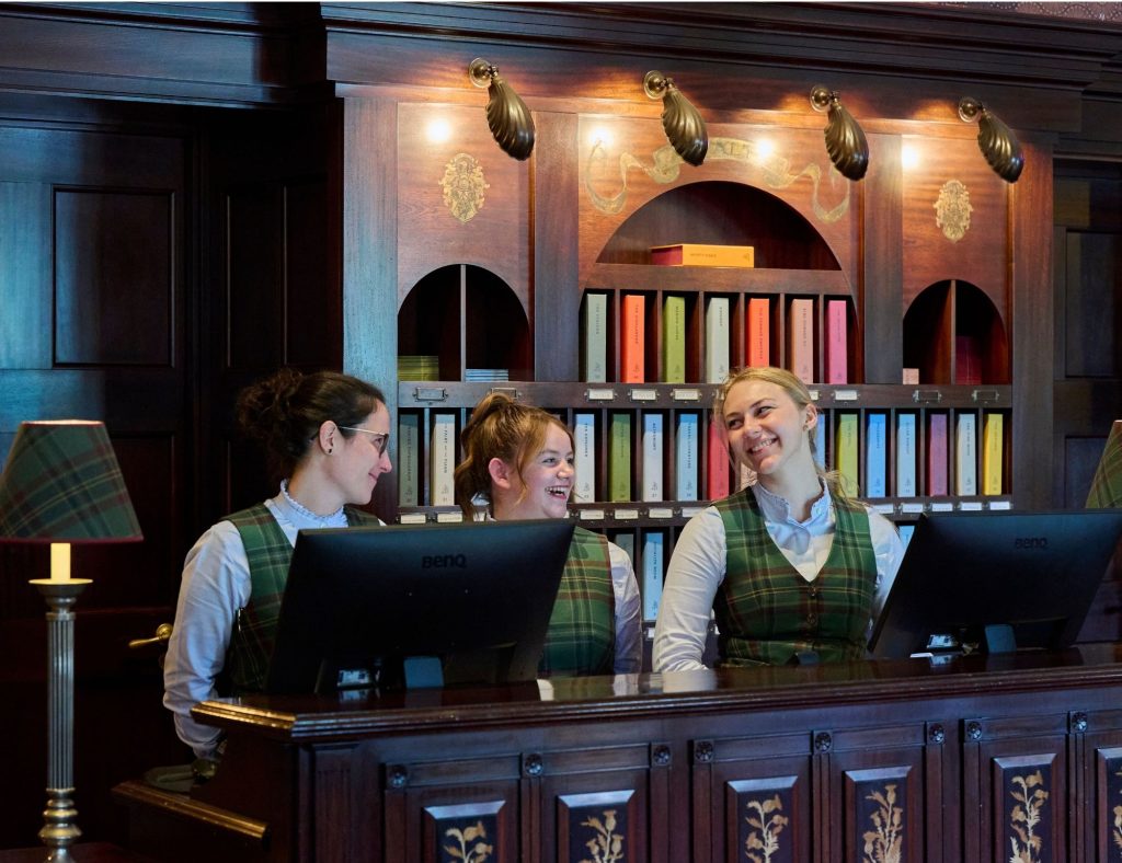 Three members of staff behind reception at the Fife Arms hotel