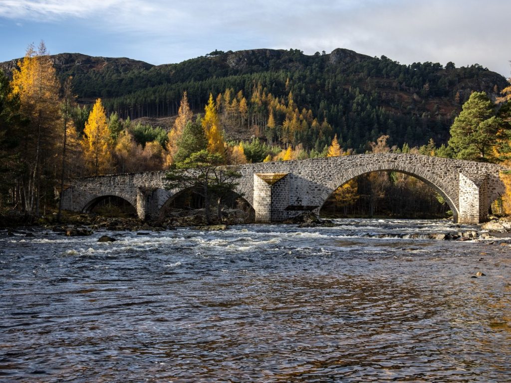 Bridge over the river dee with autumnal trees on either side.
