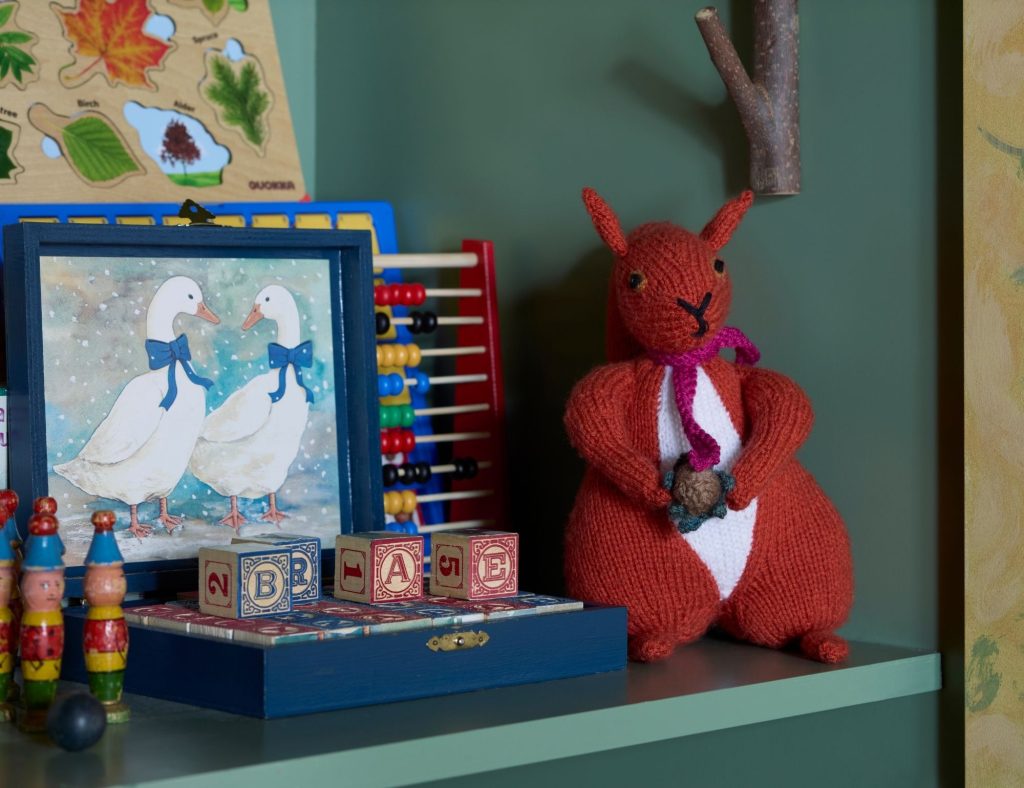 A selection of toys and a knitted squirrel on the shelf in our activity room for children
