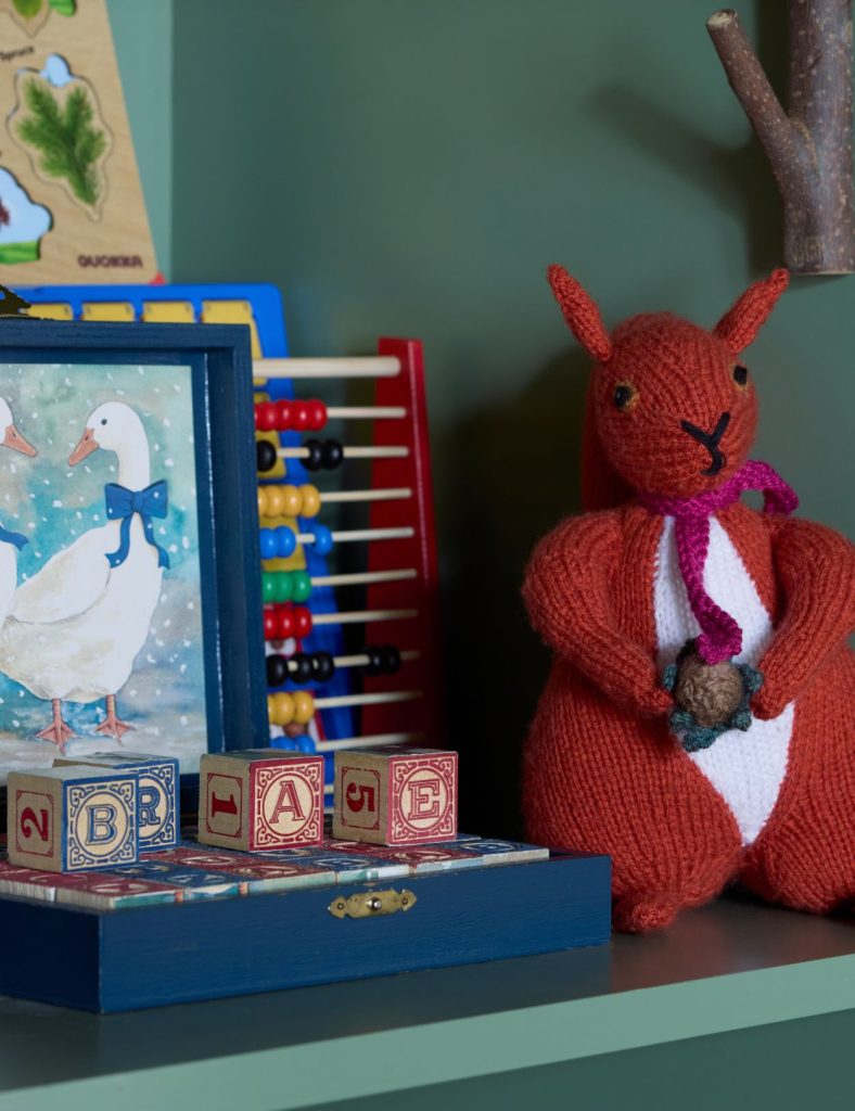 Toys on a shelf in a children's playroom, including a stuffed squirrel and building blocks.