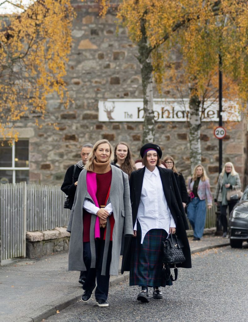 Two Festival of Fashion goers walking on the pavement wearing fashionable clothing.