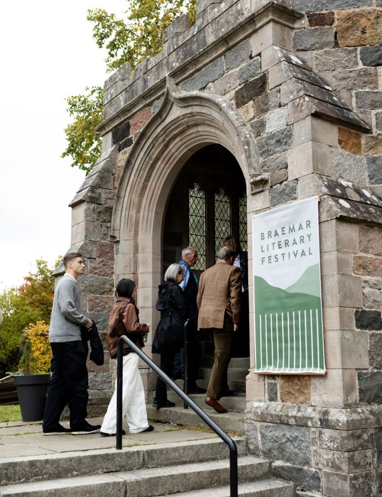 Four guests entering a church via a stone archway, a venue used for the Braemar Literary Festival.